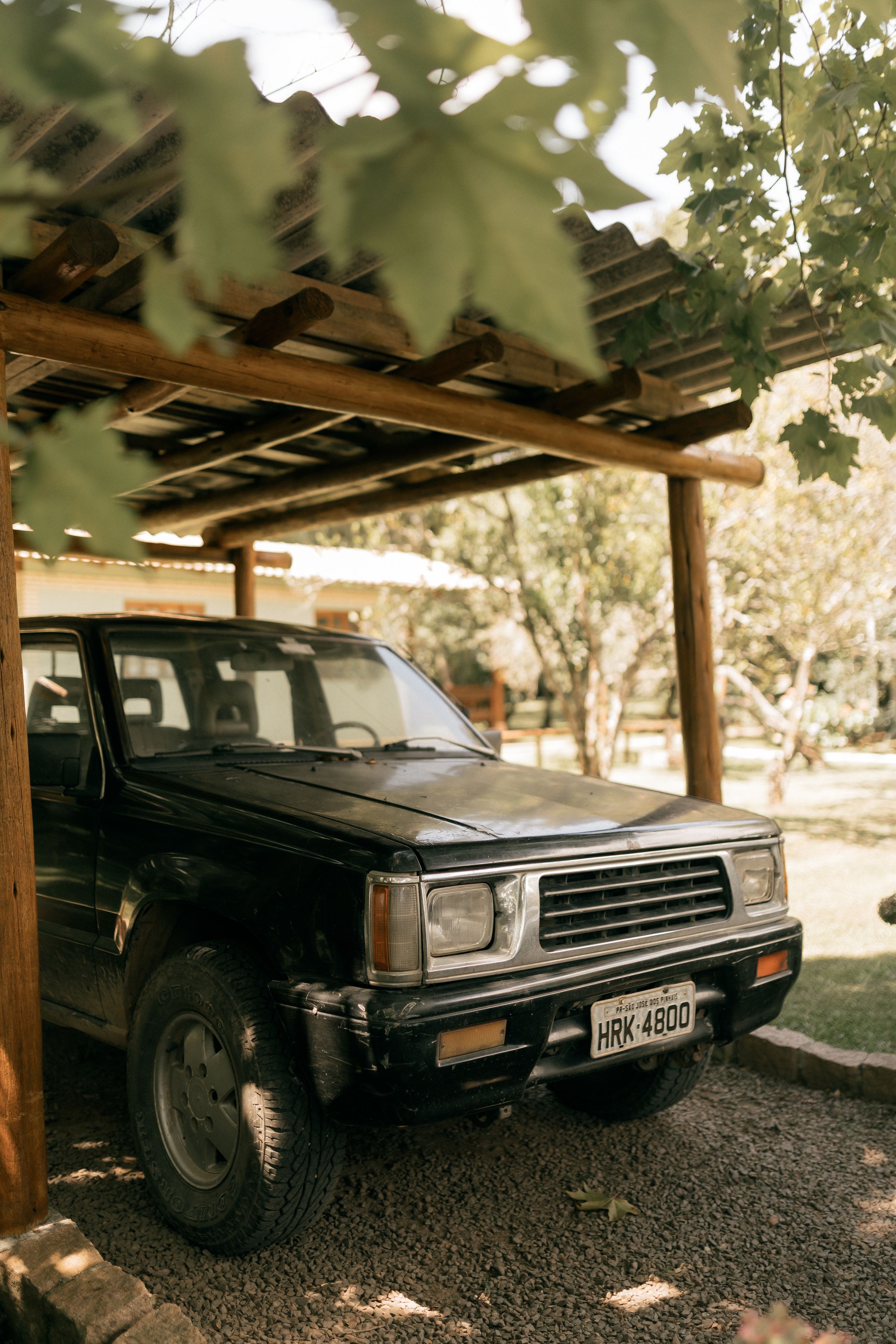 Carport en bois à charpente apparente abritant un véhicule